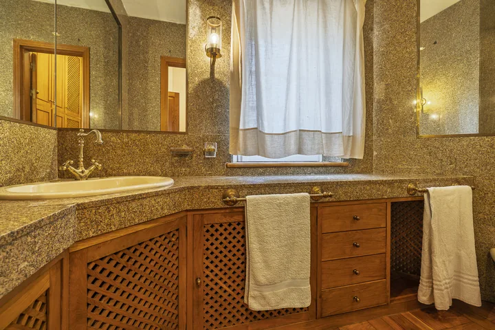 Bagno con piano in pietra e arredi in legno